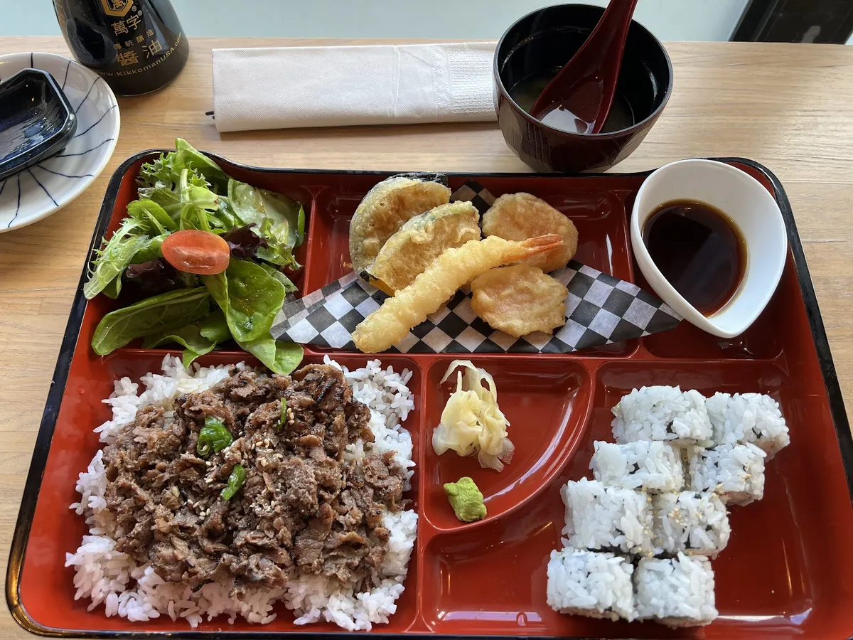 Japanese bento box with beef, rice, tempura, and sushi