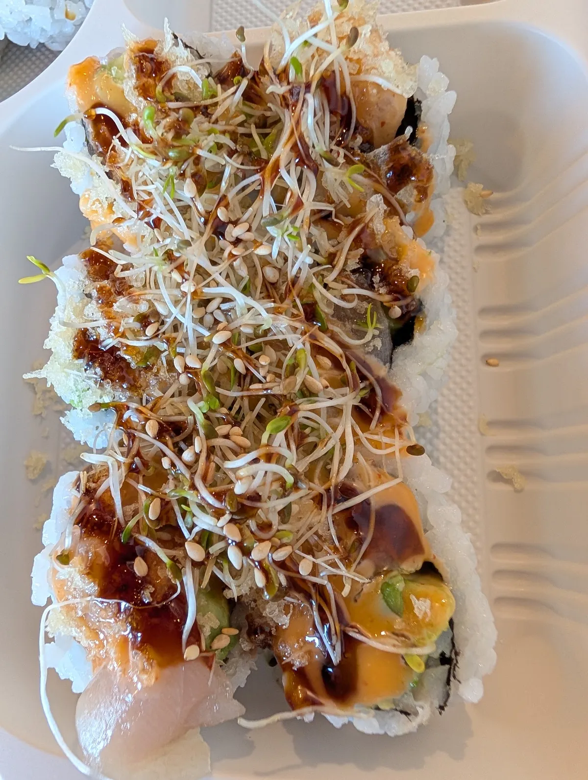 Sushi roll with sprouts, sesame seeds, and sauce